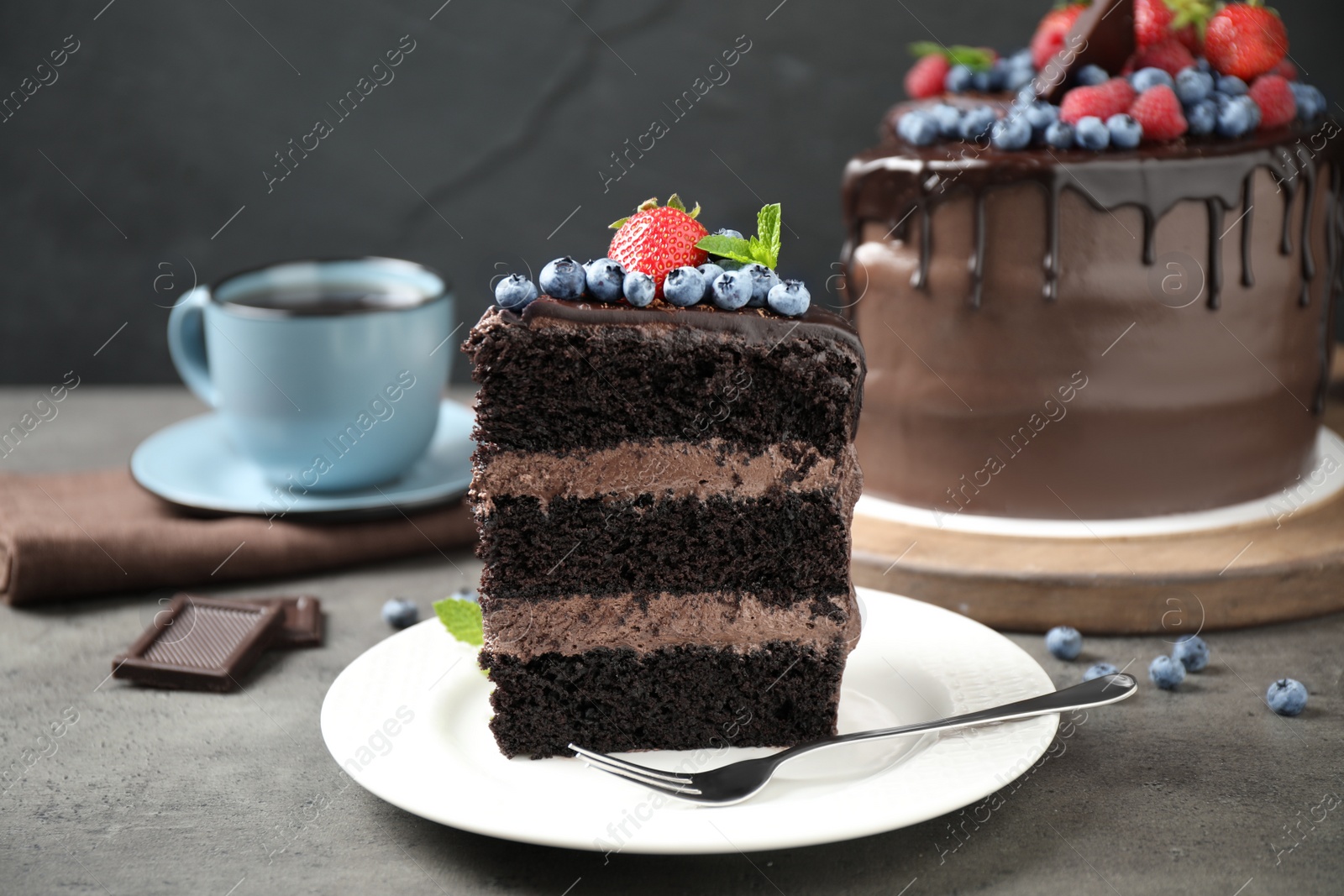 Photo of Piece of delicious chocolate cake decorated with fresh berries on grey table