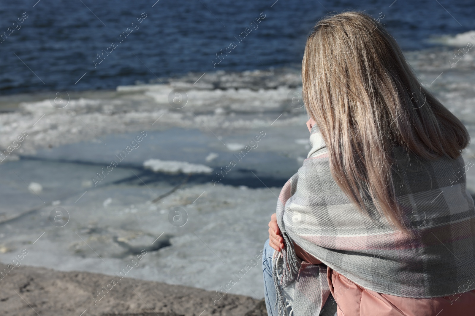 Photo of Lonely woman near river on sunny day, back view