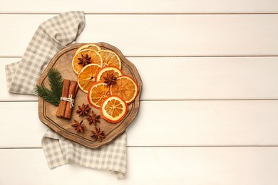 Photo of Flat lay composition with dry orange slices, anise stars and cinnamon sticks on white wooden table. Space for text