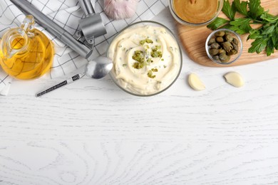 Photo of Tasty tartar sauce and ingredients on white wooden table, flat lay. Space for text