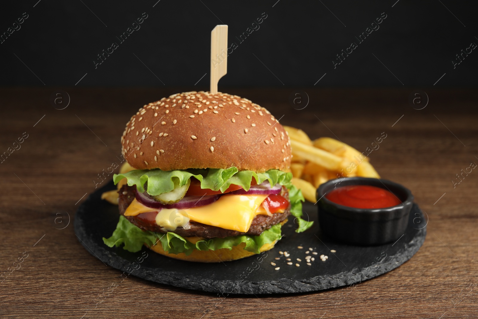 Photo of Delicious burger with beef patty, tomato sauce and french fries on wooden table