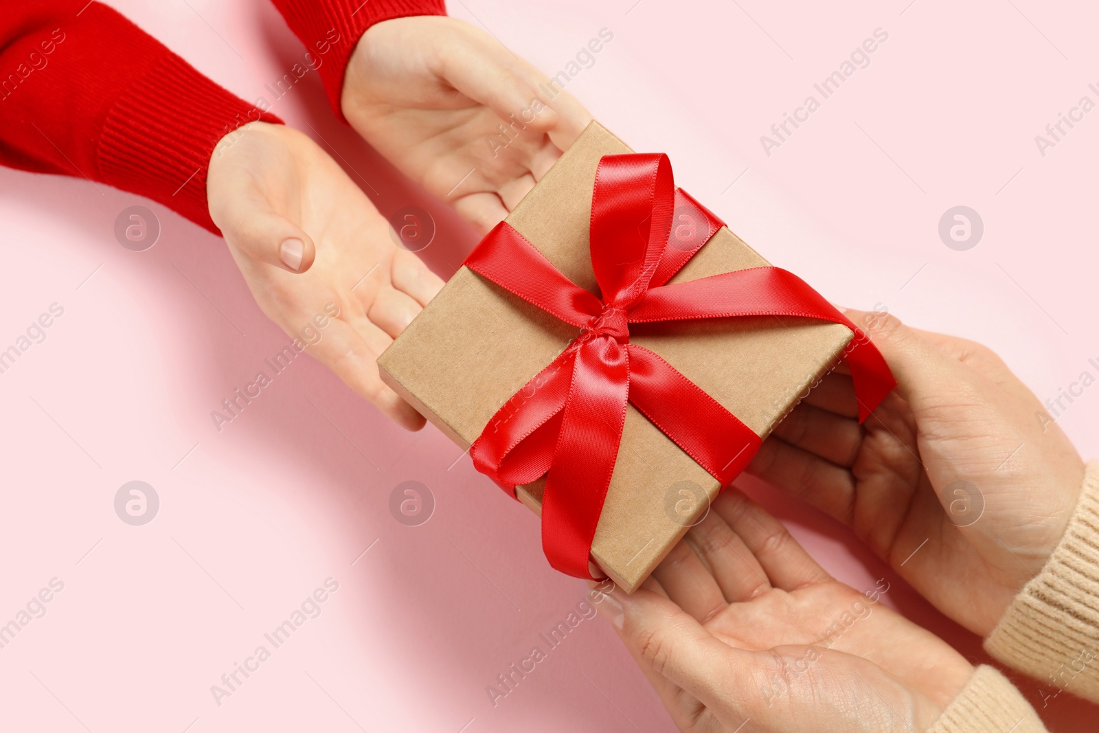 Photo of Mother giving gift box to her child on pink background, above view