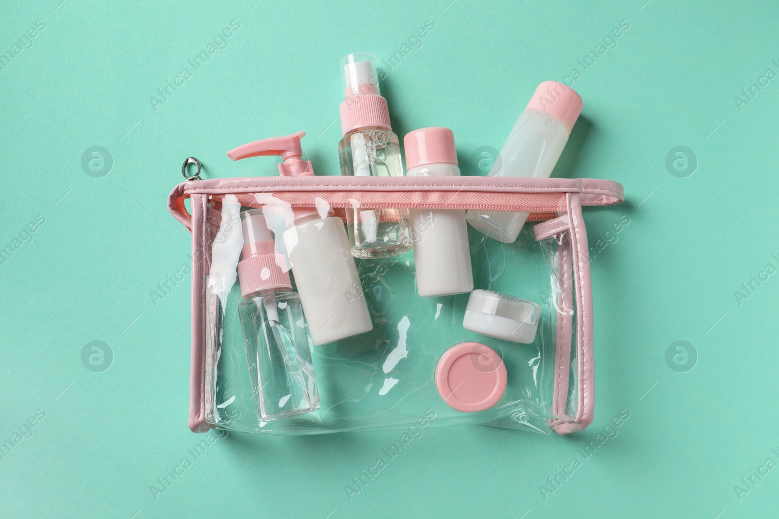 Photo of Plastic bag with cosmetic travel kit on turquoise background, top view. Bath accessories