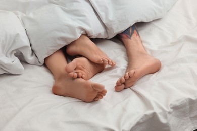 Photo of Passionate couple having sex on bed, closeup of legs