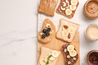 Toasts with different nut butters and products on white marble table, flat lay. Space for text