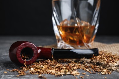 Photo of Smoking pipe with tobacco on grey table