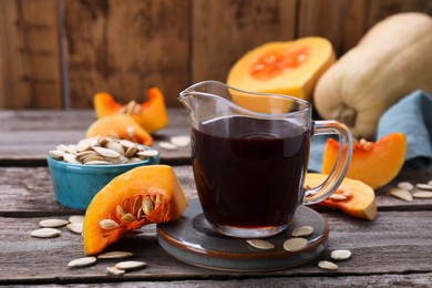 Photo of Fresh pumpkin seed oil in glass pitcher on wooden table