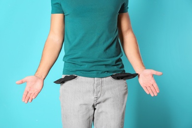 Man showing empty pockets on color background, closeup