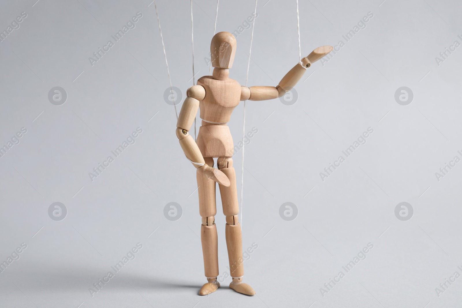 Photo of One wooden puppet with strings on light grey background