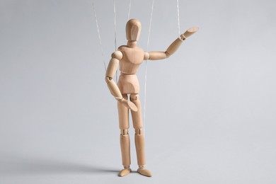Photo of One wooden puppet with strings on light grey background