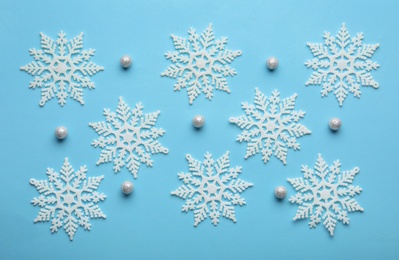 Beautiful snowflakes and decorative balls on light blue background, flat lay