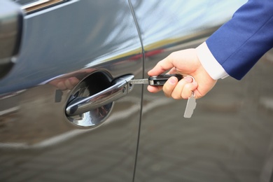 Closeup view of man opening car door with key