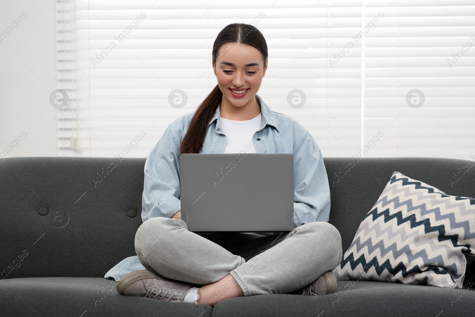 Photo of Woman using laptop on couch at home