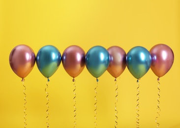 Bright balloons with ribbons on color background