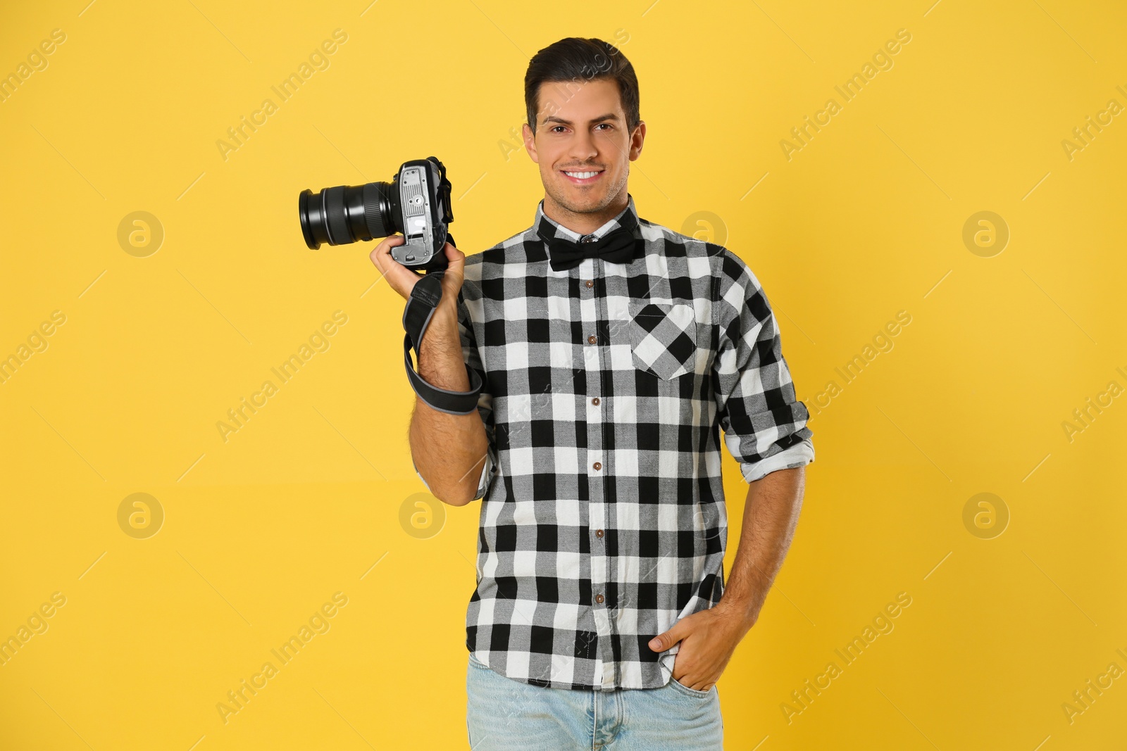 Photo of Professional photographer working on yellow background in studio