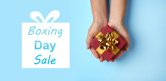 Boxing day sale. Top view of woman with gift on light blue background, banner design