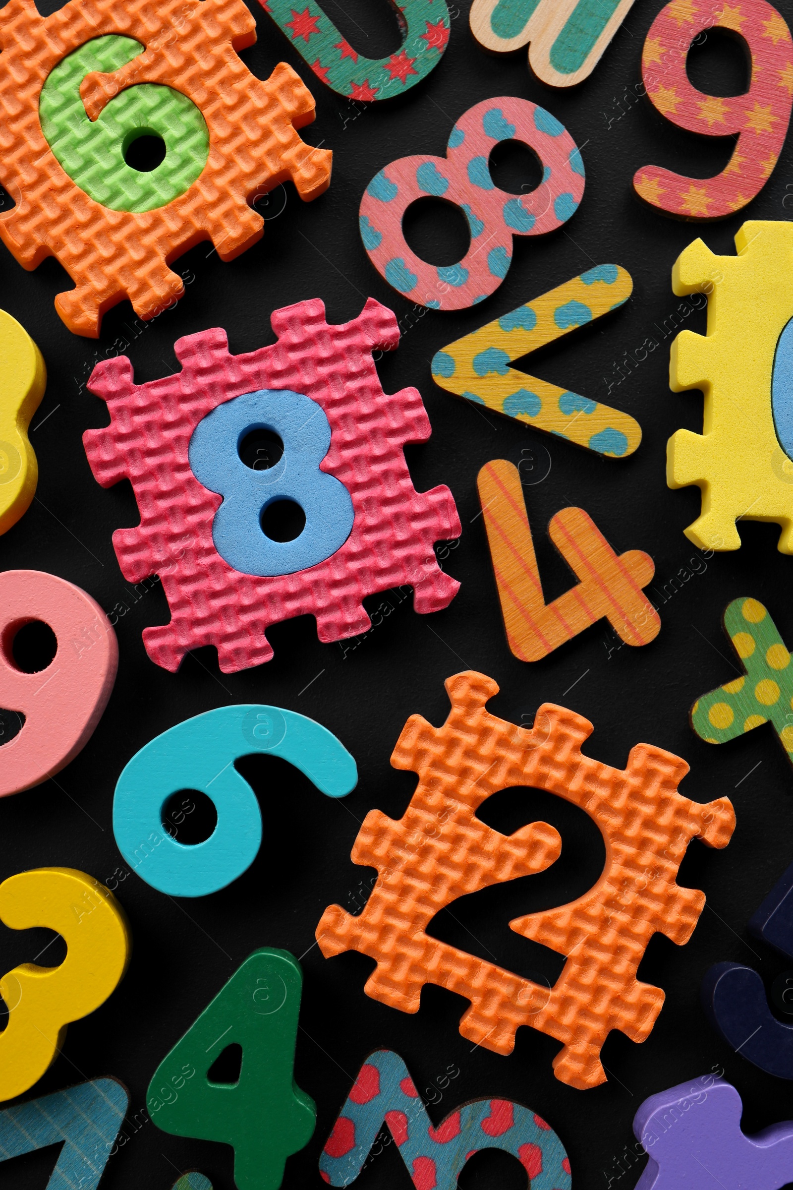 Photo of Many colorful numbers and mathematical symbols on black background, flat lay