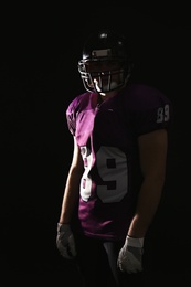 Photo of American football player wearing uniform on dark background