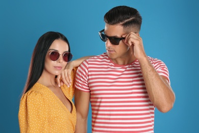 Photo of Stylish couple wearing sunglasses on blue background