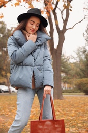 Photo of Young woman wearing stylish clothes in autumn park