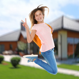 Image of Happy teenage girl jumping near house. School holidays