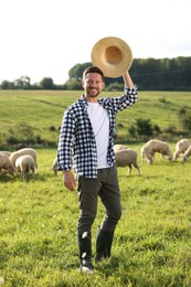 Photo of Smiling man tipping hat on pasture at farm