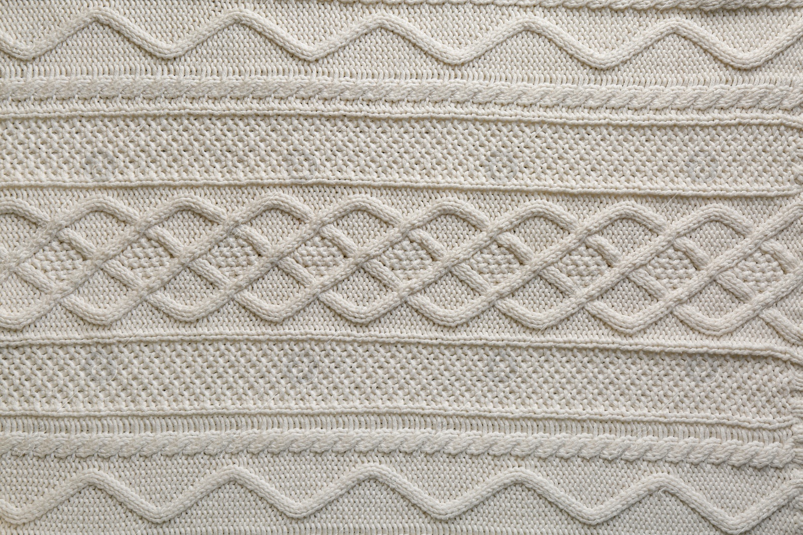 Photo of White knitted fabric with beautiful pattern as background, top view