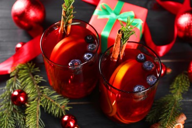 Aromatic Sangria drink in glasses, ingredients and Christmas decor on black wooden table