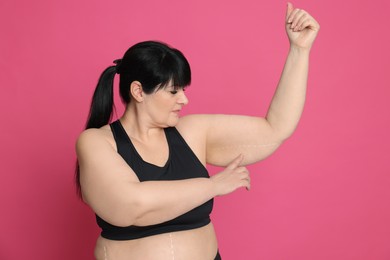 Photo of Obese woman with flabby arm on pink background. Weight loss surgery