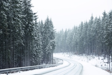 Photo of Beautiful landscape with conifer forest and road on snowy winter day