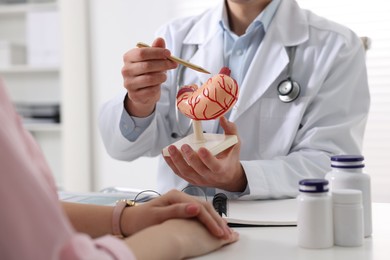 Photo of Gastroenterologist with human stomach model consulting patient at table in clinic, closeup