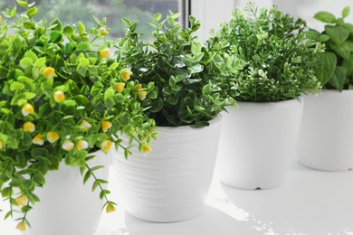 Artificial potted herbs on sunny day on windowsill indoors, closeup. Home decor
