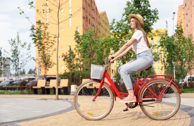 Young pretty woman riding bicycle in city. Space for text