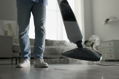 Man cleaning floor with steam mop at home, closeup