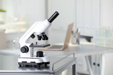 Photo of Modern medical microscope on metal table in laboratory. Space for text