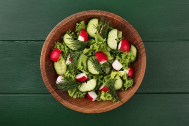 Photo of Delicious salad with radish, lettuce, dill and cucumber on green wooden table, top view