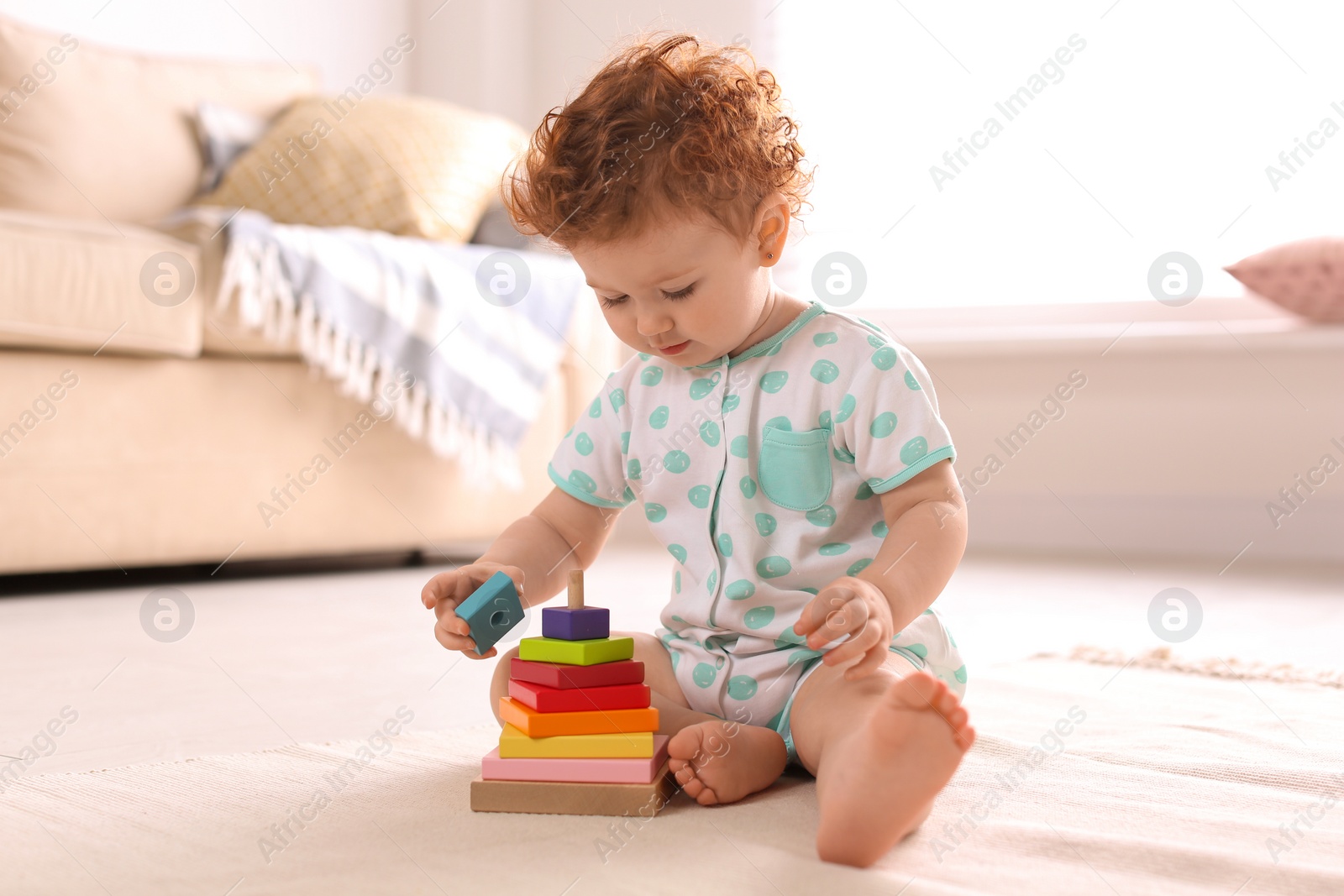 Photo of Cute little child playing with toy on floor at home