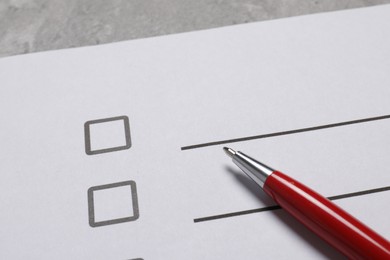 Photo of Paper sheet with checkboxes and pen on light grey table, closeup. Checklist