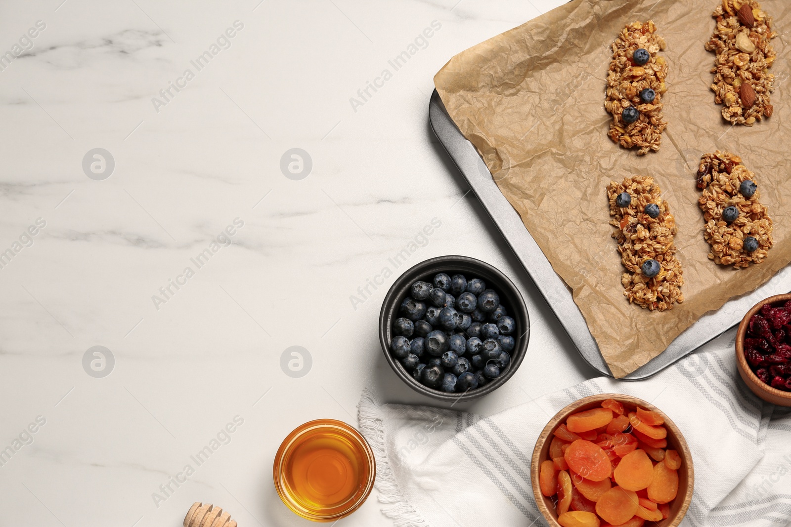 Photo of Making granola bars. Baking tray and ingredients on white marble table, flat lay. Space for text