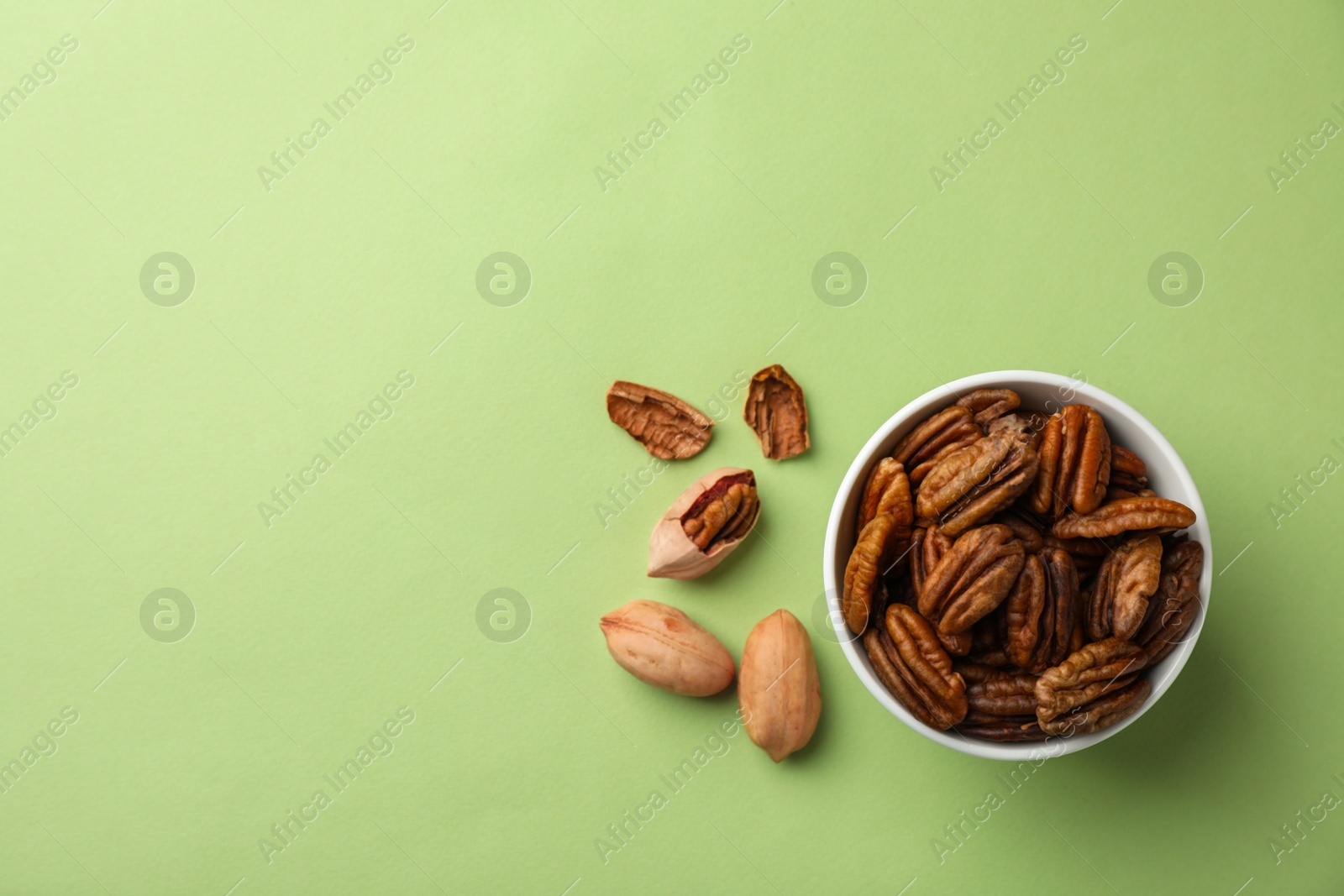 Photo of Flat lay composition with pecan nuts in dish on color background. Space for text