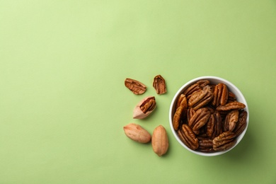 Photo of Flat lay composition with pecan nuts in dish on color background. Space for text