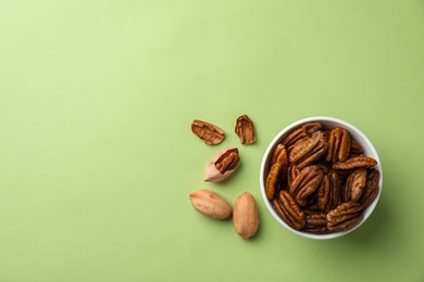 Flat lay composition with pecan nuts in dish on color background. Space for text