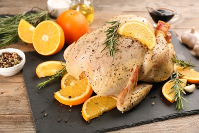 Photo of Raw chicken, orange slices and other ingredients on wooden table