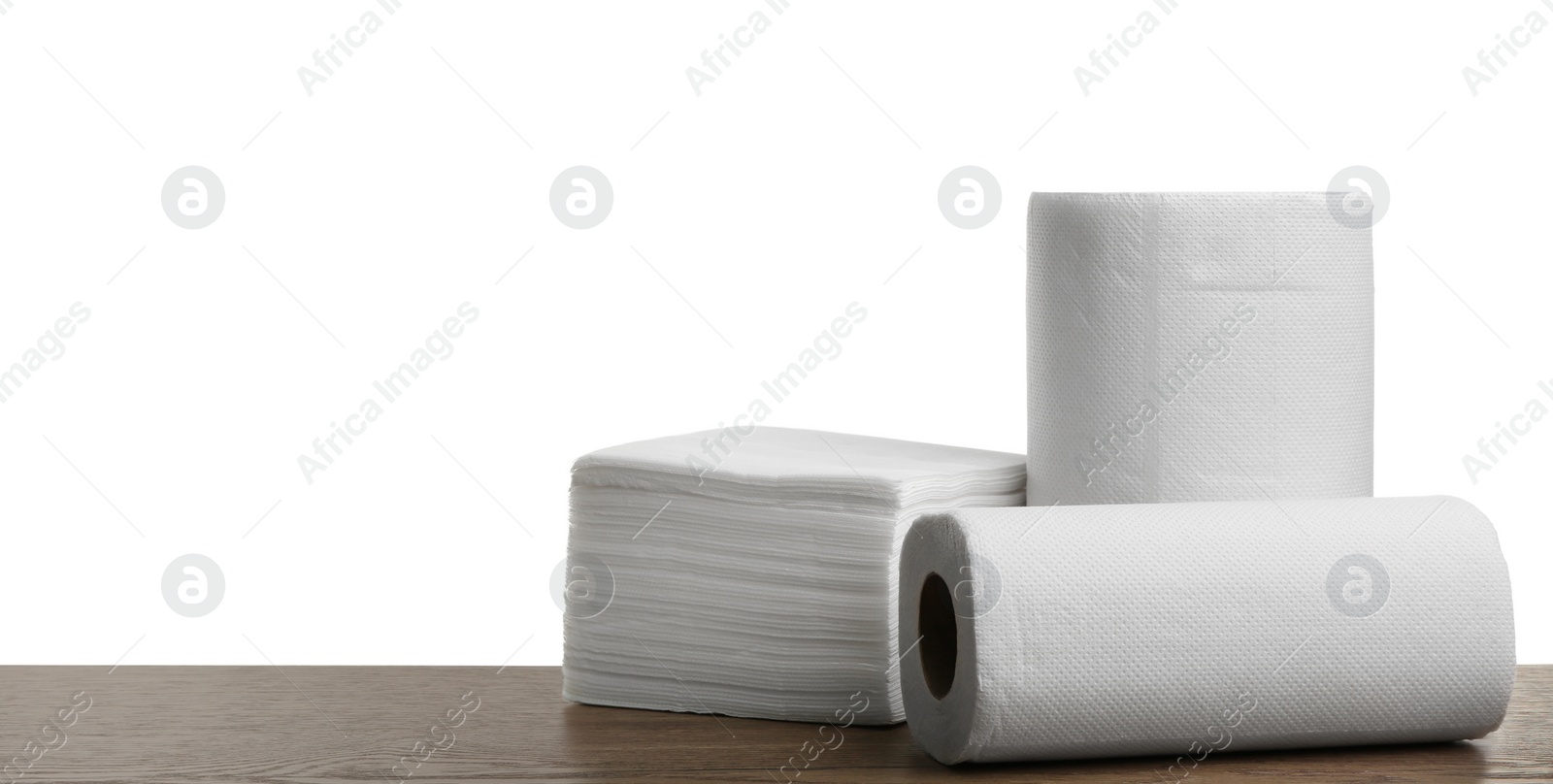 Photo of Rolls and stack of clean paper tissues on wooden table against white background