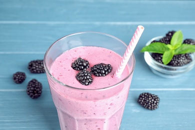 Delicious blackberry smoothie in glass on blue wooden table