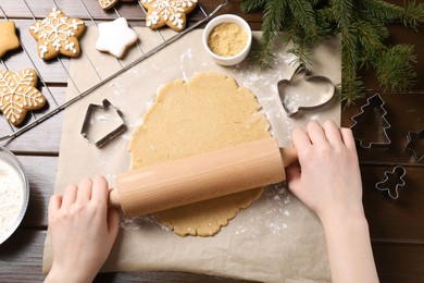 Making Christmas cookies. Woman rolling raw dough at wooden table, top view