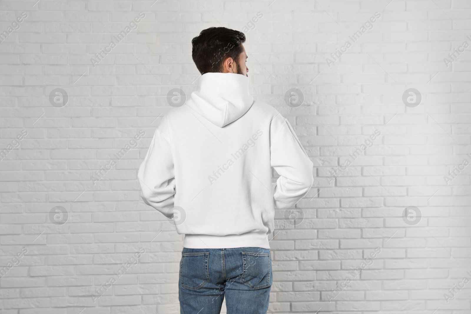 Photo of Young man in sweater at brick wall. Mock up for design