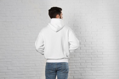 Young man in sweater at brick wall. Mock up for design