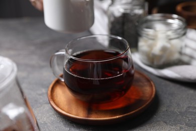 Photo of Tasty hot tea in cup on grey table, closeup