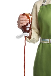 Woman pouring tasty ketchup from bottle on white background, closeup